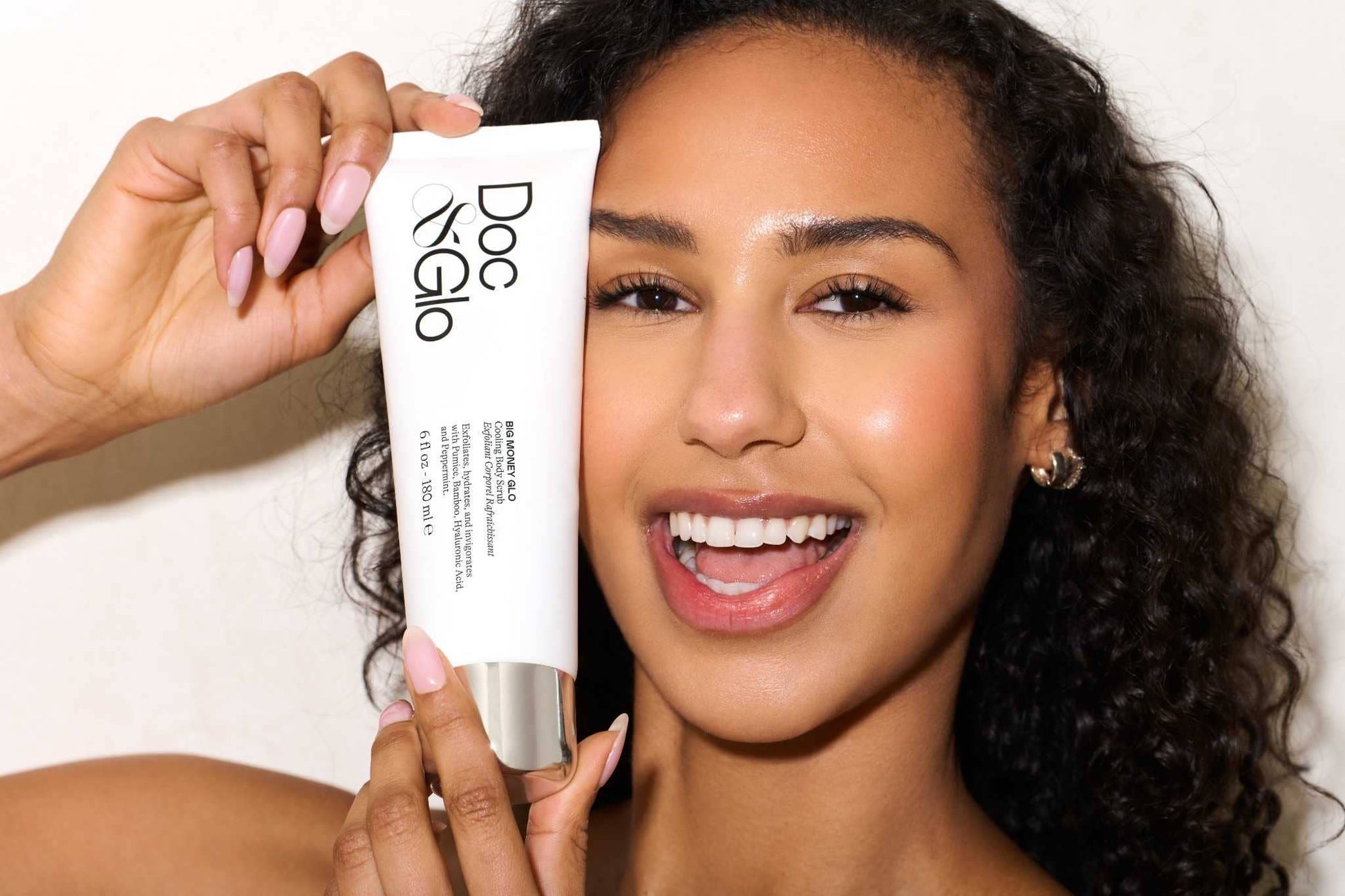 Woman holding a Cooling Body Scrub skincare with a plain background