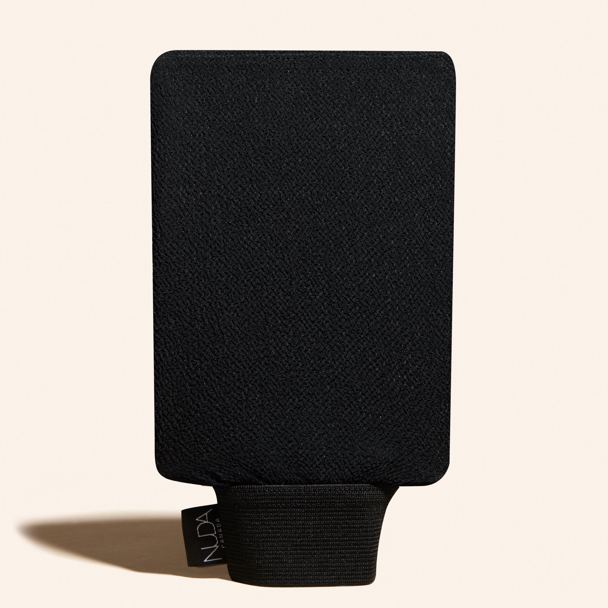 Black mitt with a brand tag on a beige background