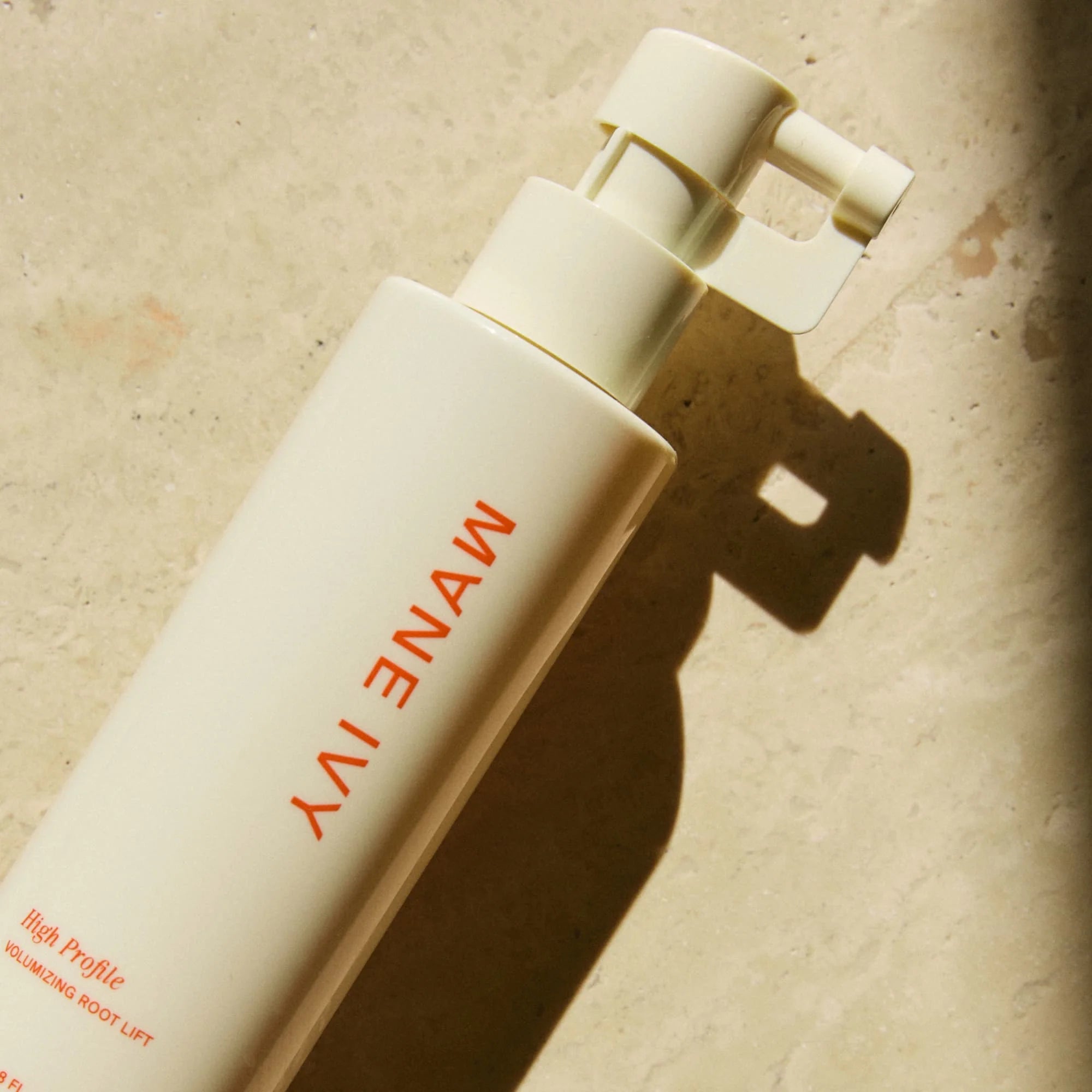 Mane ivy hair product bottle on a textured beige background