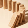 A group of NUDA liquid foundation bottles in a warm beige shade, arranged diagonally on a matching beige studio background.