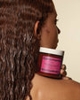 Person holding a jar of Ceremonia hair product with wet hair