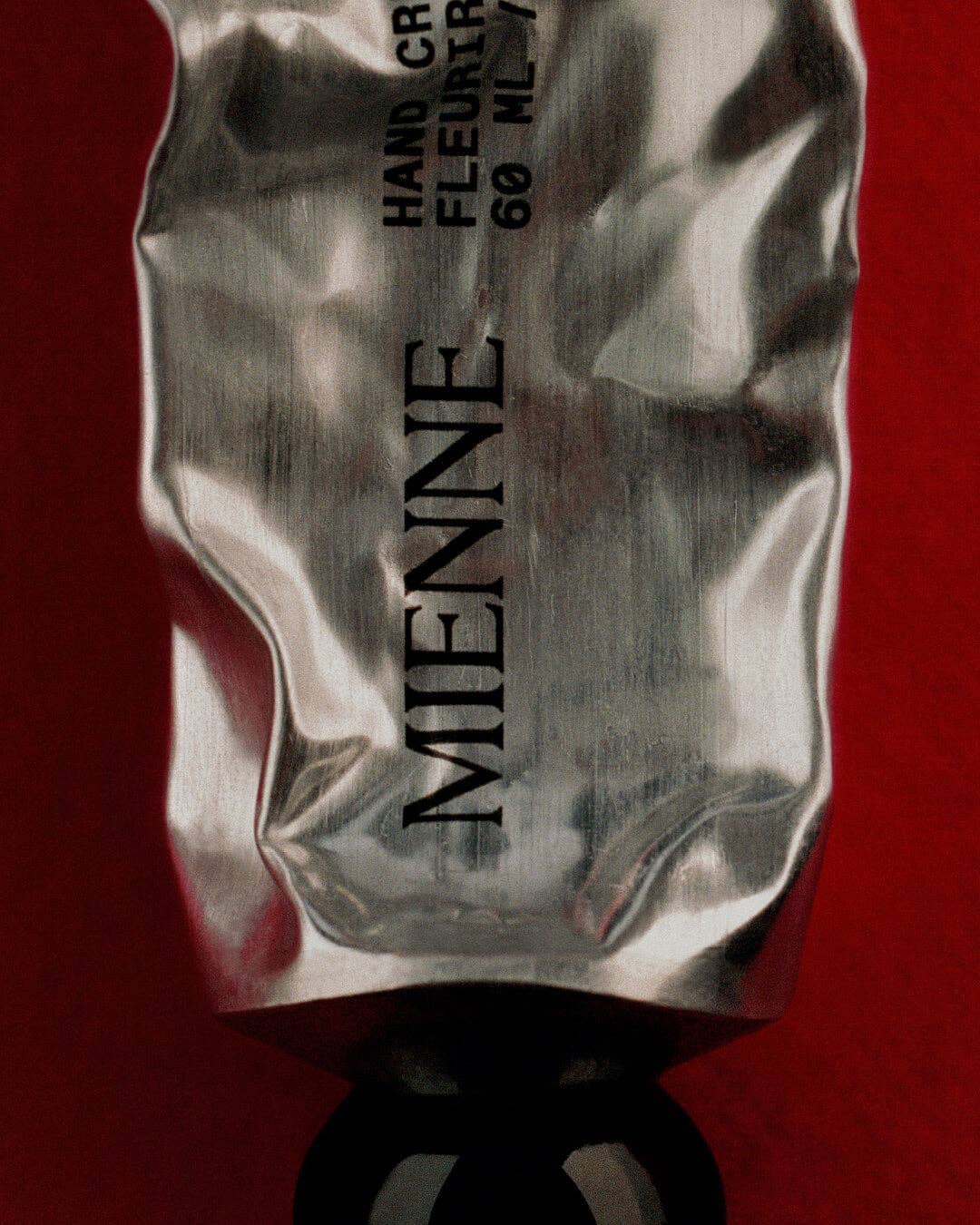 Silver tube with 'MIENNE' branding on a red background