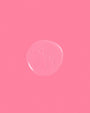 Pink background with a central circular object resembling a soap bubble or gel.