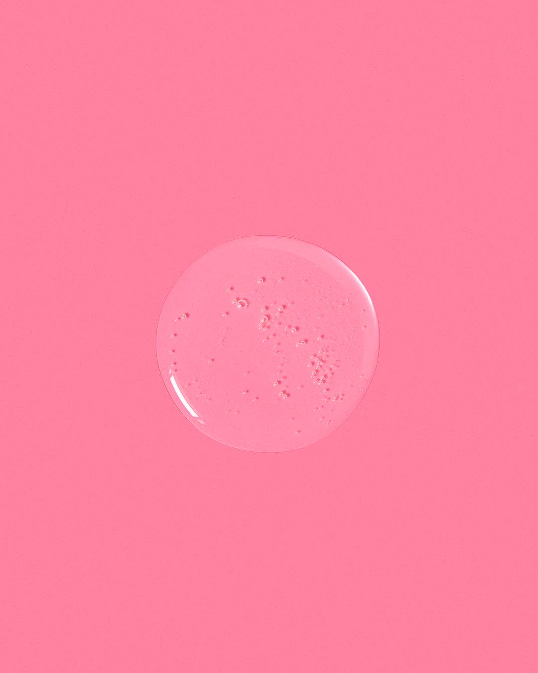 Pink background with a central circular object resembling a soap bubble or gel.