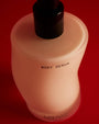 Body serum bottle with black cap on a red background