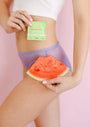 Person holding a watermelon slice with a sweat and wipe product on their stomach against a pink background