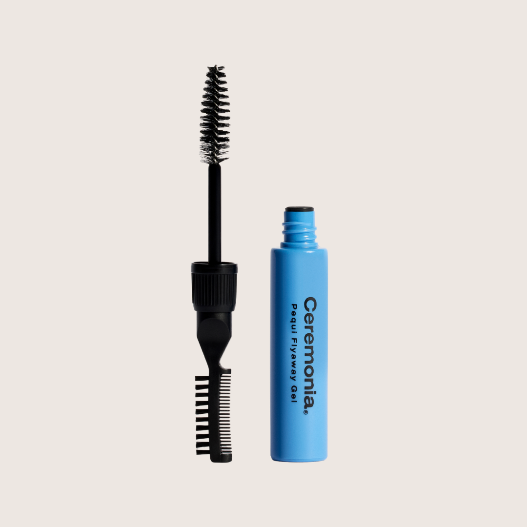 Blue mascara tube with black brush on a light beige background