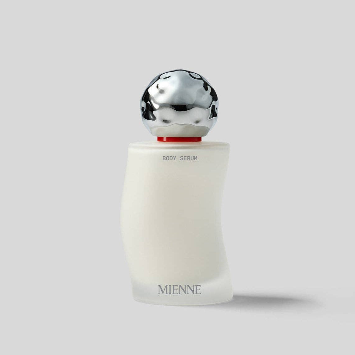 Menne body serum bottle with silver cap on a light gray background