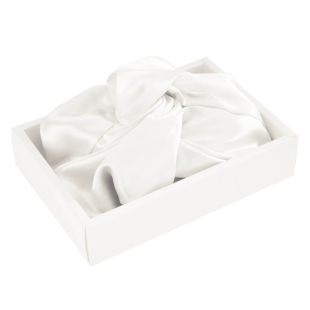 White silk bonnet with a bow in a box on a white background