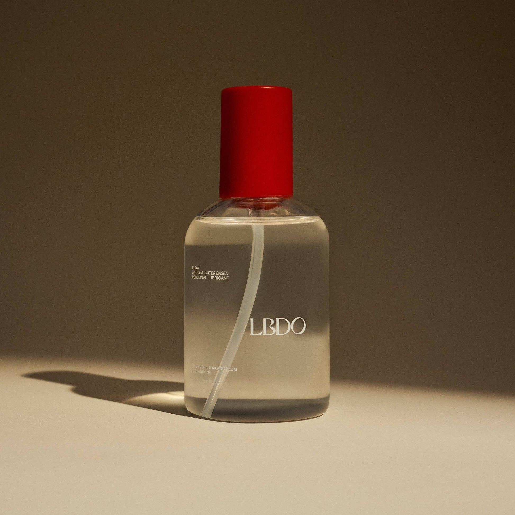 Clear bottle with red cap on a beige background
