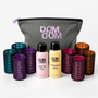 Dom Dom hair care set featuring a gray zippered pouch with pink lettering, two bottles of hair product (Hair Oil Mist in pink and Detangling Spray in yellow), and multiple stacks of colorful silicone hair rollers in purple, teal, magenta, and brown, arranged on a white background.