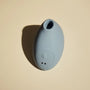 A light blue silicone personal massager with a minimalist teardrop shape, shown from a top-down angle on a beige background with a soft shadow.