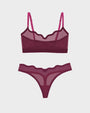 A two-piece lingerie set featuring a sheer mesh bralette and matching thong in a deep magenta color, displayed on a light gray background.