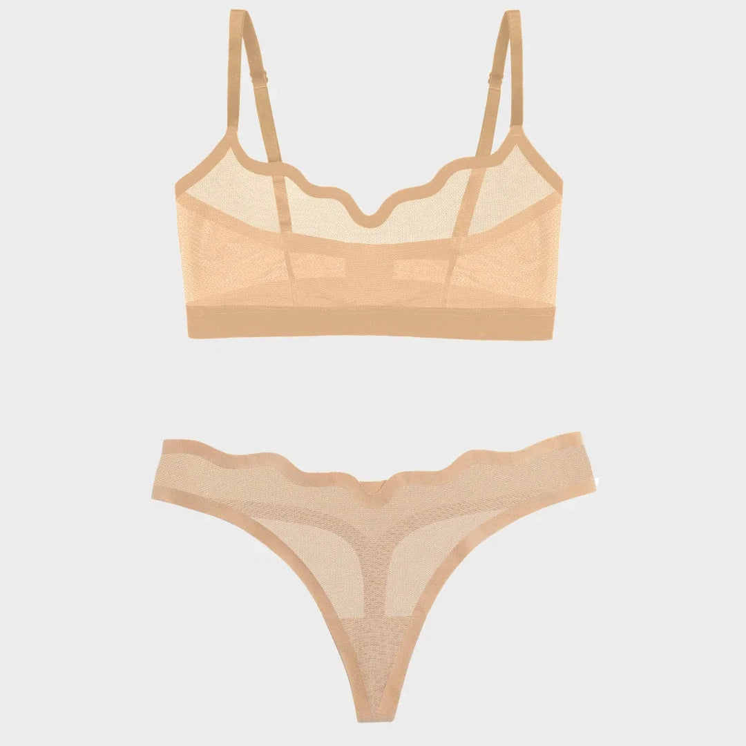 A two-piece sheer lingerie set in a light peach-beige color, featuring a scalloped underwire bralette and matching thong with mesh panels and lace trim, displayed on a light gray background.