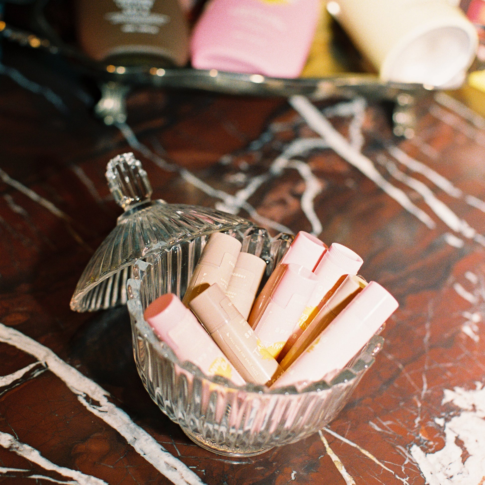 chapstic in glass bowl against a marble backgorund