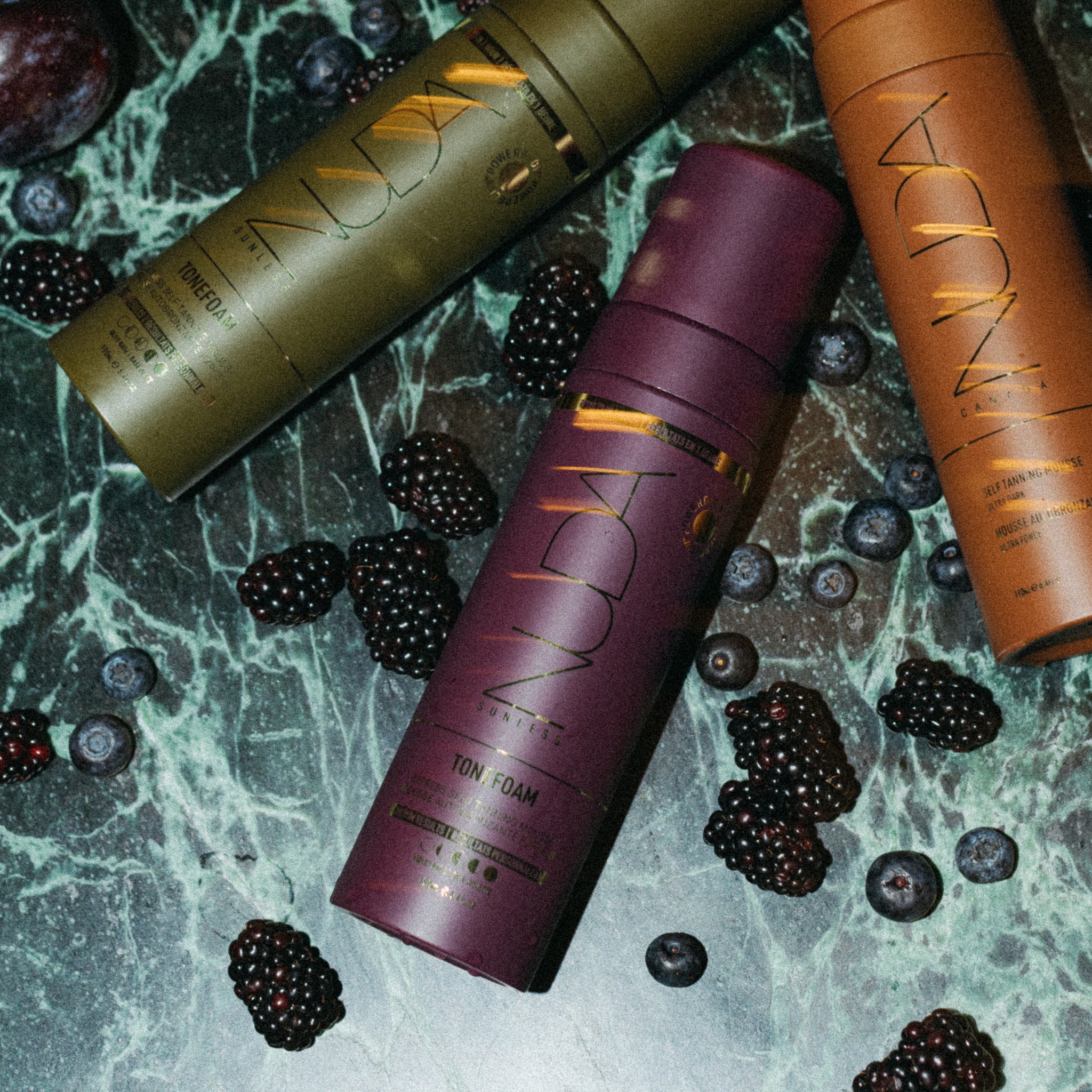 nuda self tanners laying flat on a green marble surface