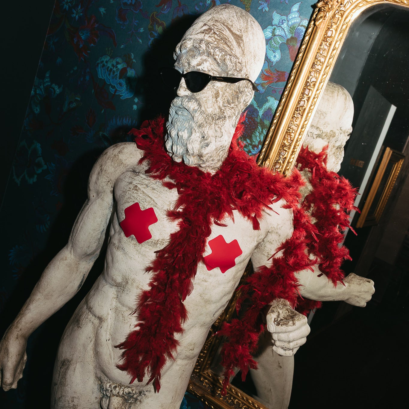 Statue with red cloths and sunglasses in a decorative room with a mirror.