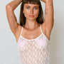 Woman wearing a white lace camisole with pink floral details against a plain background