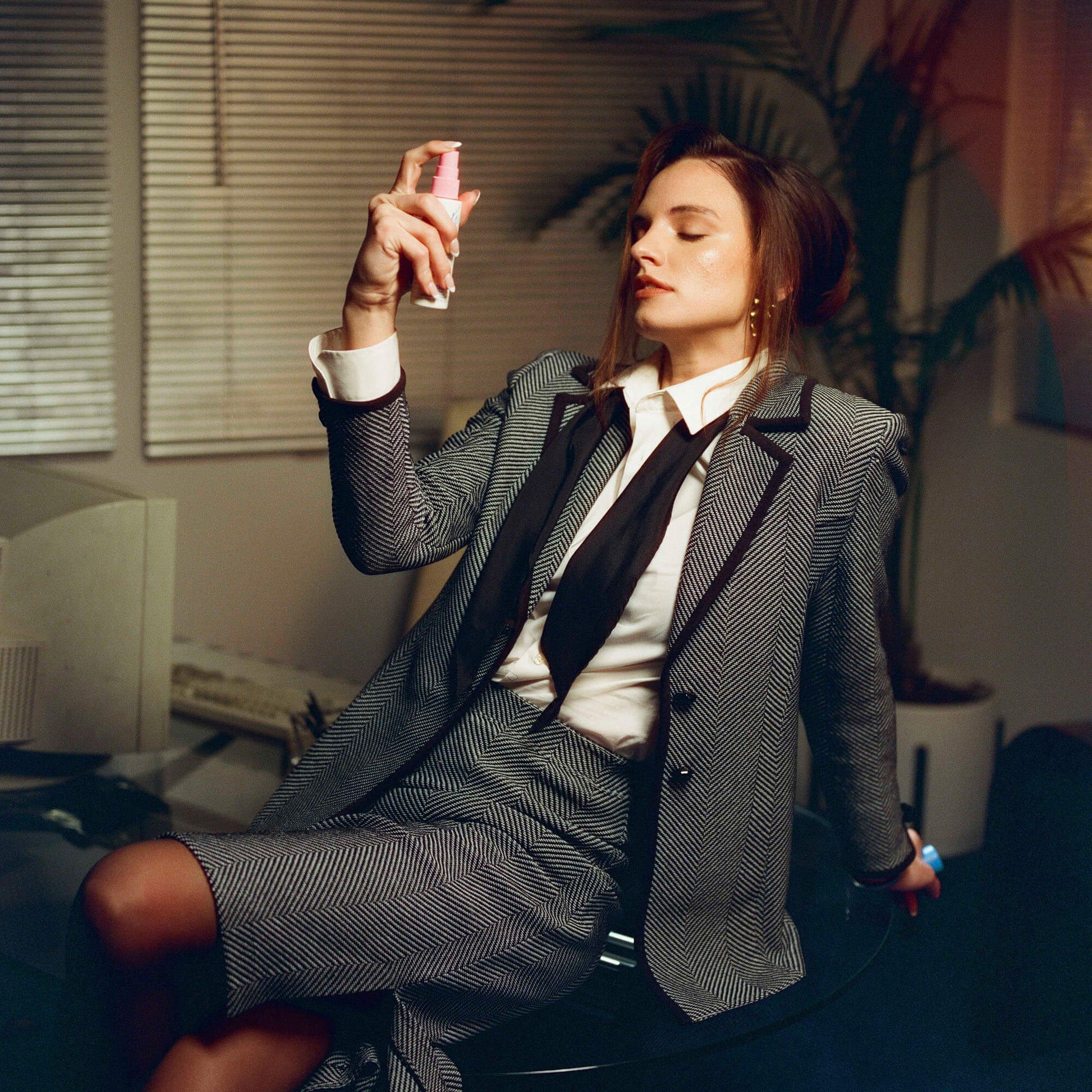 Woman in a suit sitting in an office with a plant in the background
