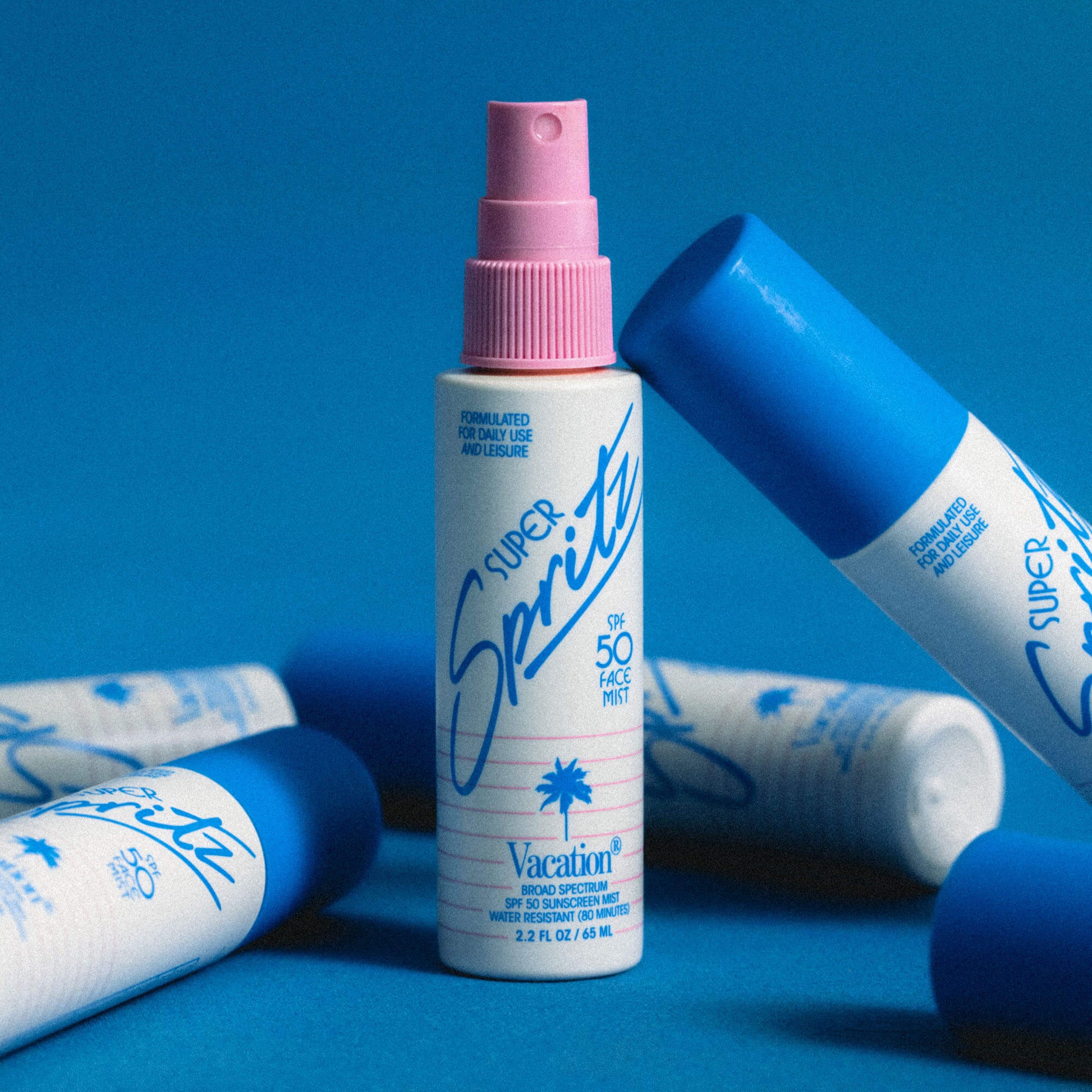 Super Sprite sunscreen bottle with pink spray top on a blue background