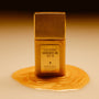 Gold bottle of 'Vacation Shimmer Oil SPF 30' on a beige background