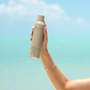 Hand holding a bottle of 'Dolce Glow' product against a gradient blue background