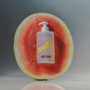 Nudie body wash bottle inside a watermelon on a gray background