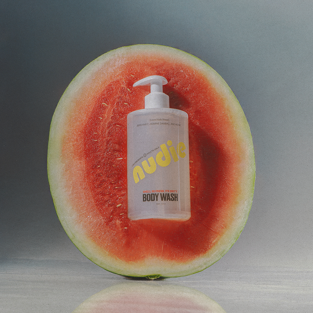 Nudie body wash bottle inside a watermelon on a gray background