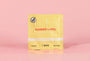 Yellow sweetums wipe on a pink background with water droplets on the pack