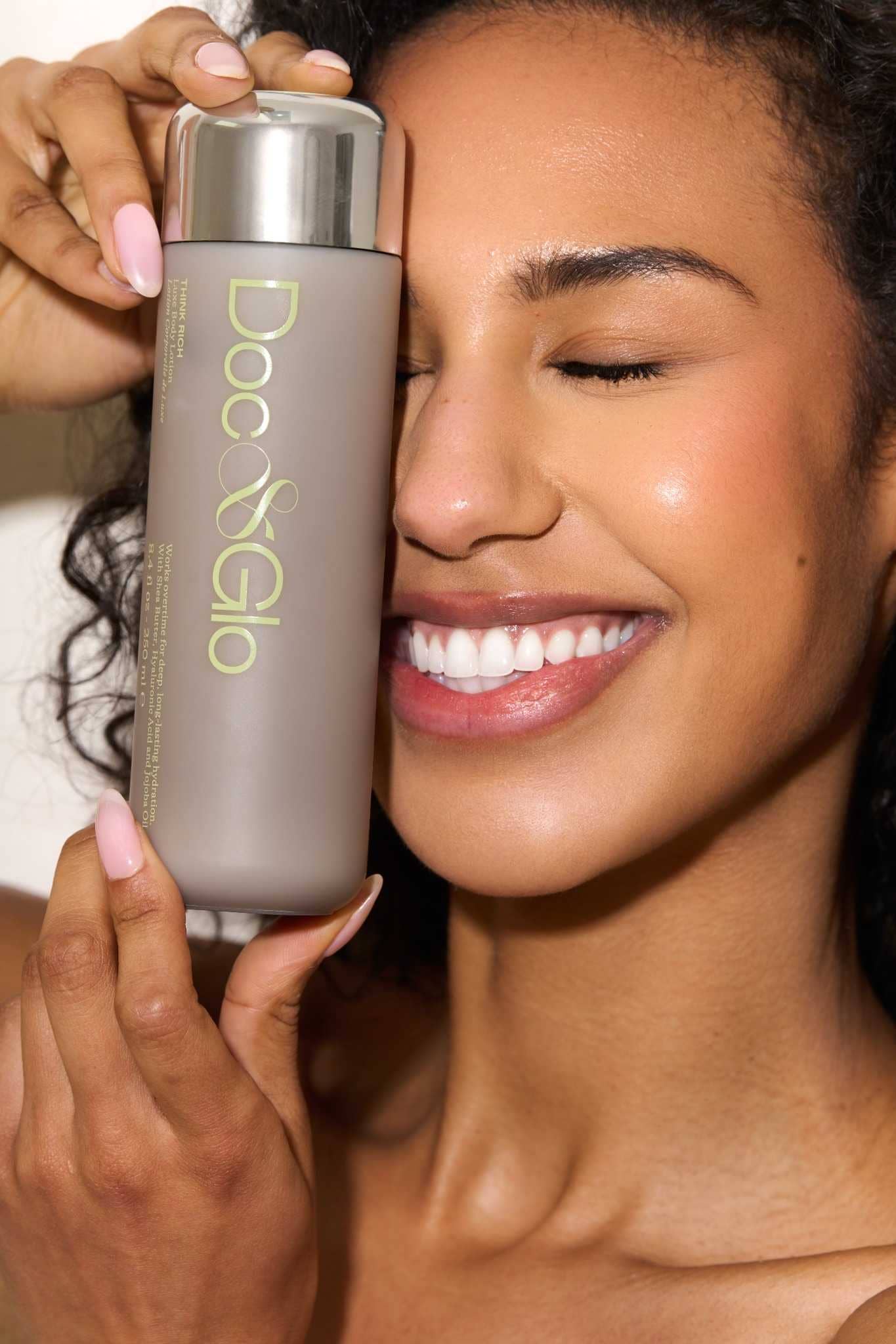 Woman holding a bottle of Think Luxe Hydating Body Lotion product close to her face