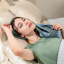Woman wearing a blue silk bonnet while lying on a bed