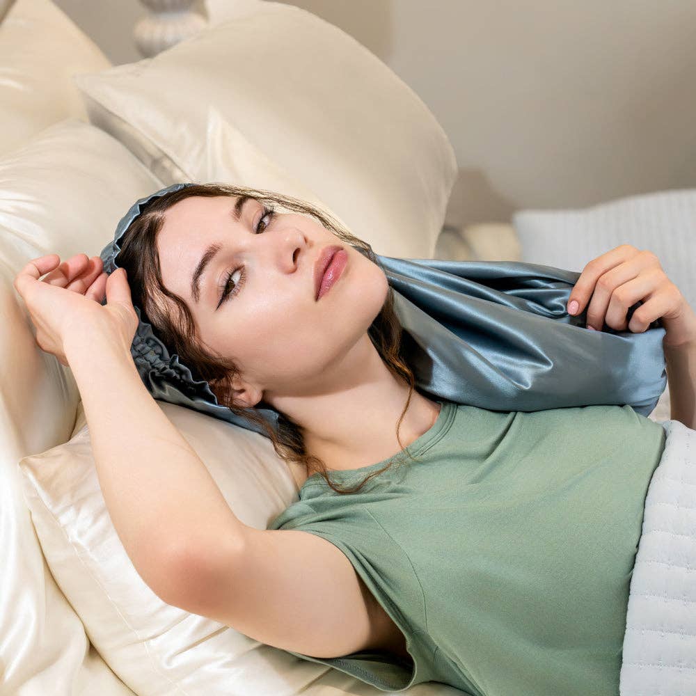 Woman wearing a blue silk bonnet while lying on a bed