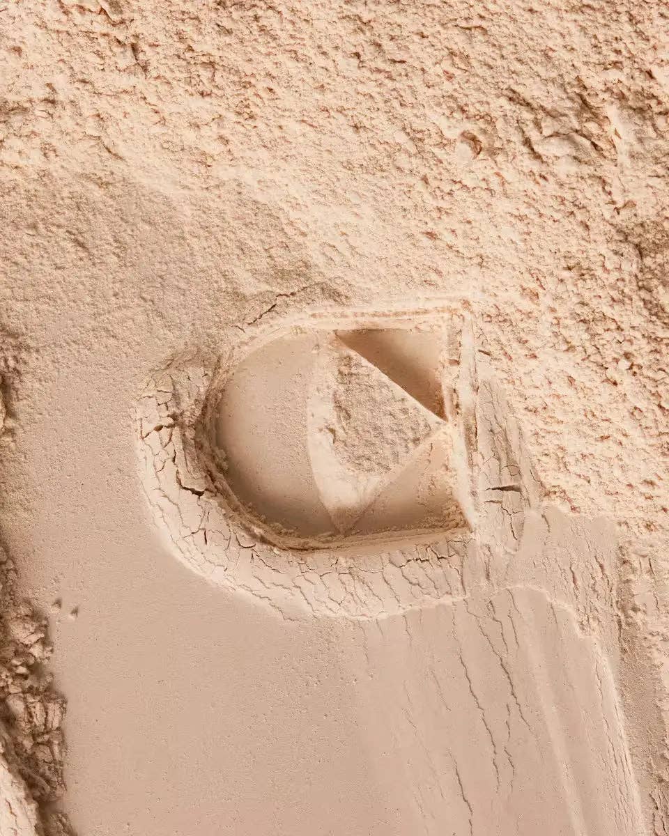 Close-up of a sandstone wall with a circular recess and square frame.