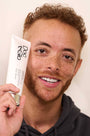 Man holding Big Money Glo Cooling Body Scrub product with a neutral background