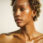 Close-up of a woman with a neutral expression and glowing skin against a light background