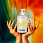 Nudie body wash bottle held by hands against a colorful background