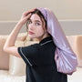 Woman wearing a satin bonnett in a bedroom setting