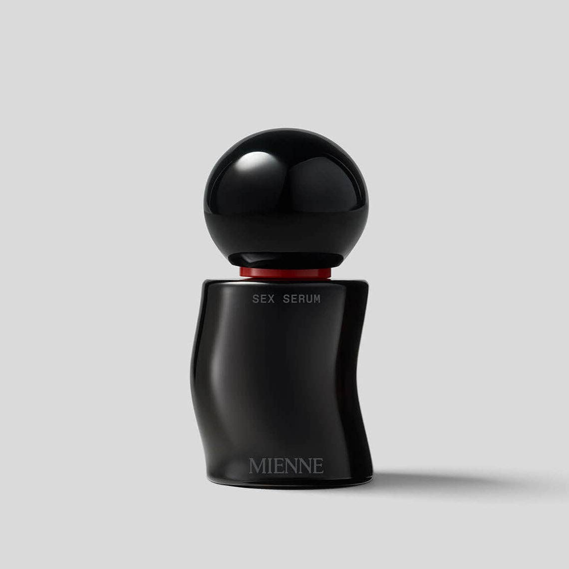 Black serum bottle with spherical cap on a light gray background